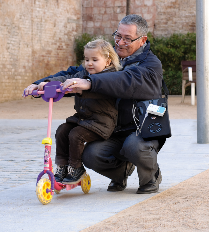 abuelo ayudando a su nieta a andar en patinete